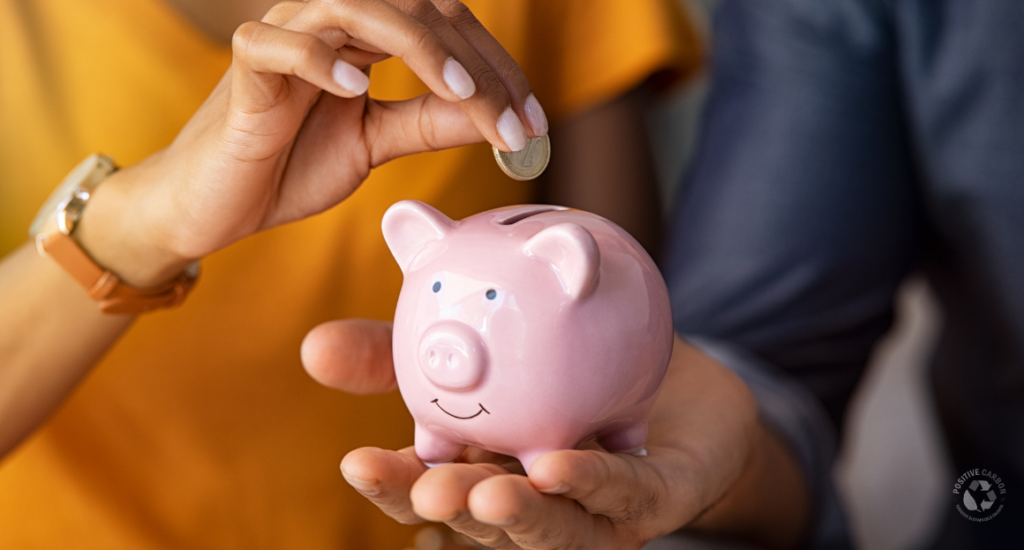 A person places a coin into a pink piggy bank, symbolising savings and reduced upfront costs through Victorian Government energy rebate programs.